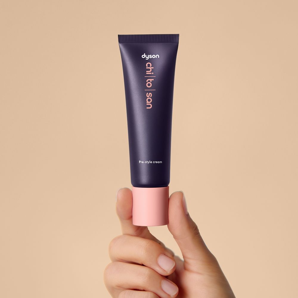 Dyson Chitosan Pre-style cream in 30ml sizing held in a hand.