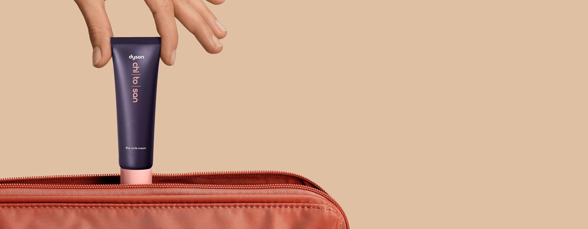 Dyson Chitosan Pre-style cream 30ml being placed into a travel bag.