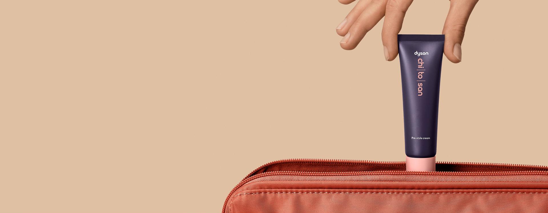 Dyson Chitosan Pre-style cream 30ml being placed into a travel bag.