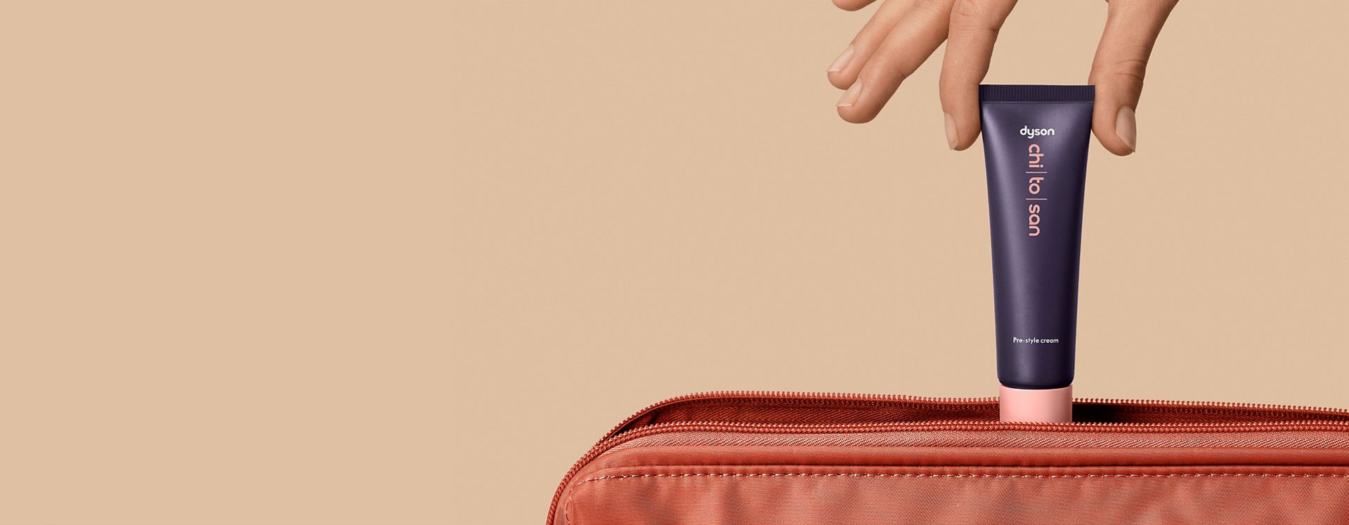 Dyson Chitosan Pre-style cream 30ml being placed into a travel bag.