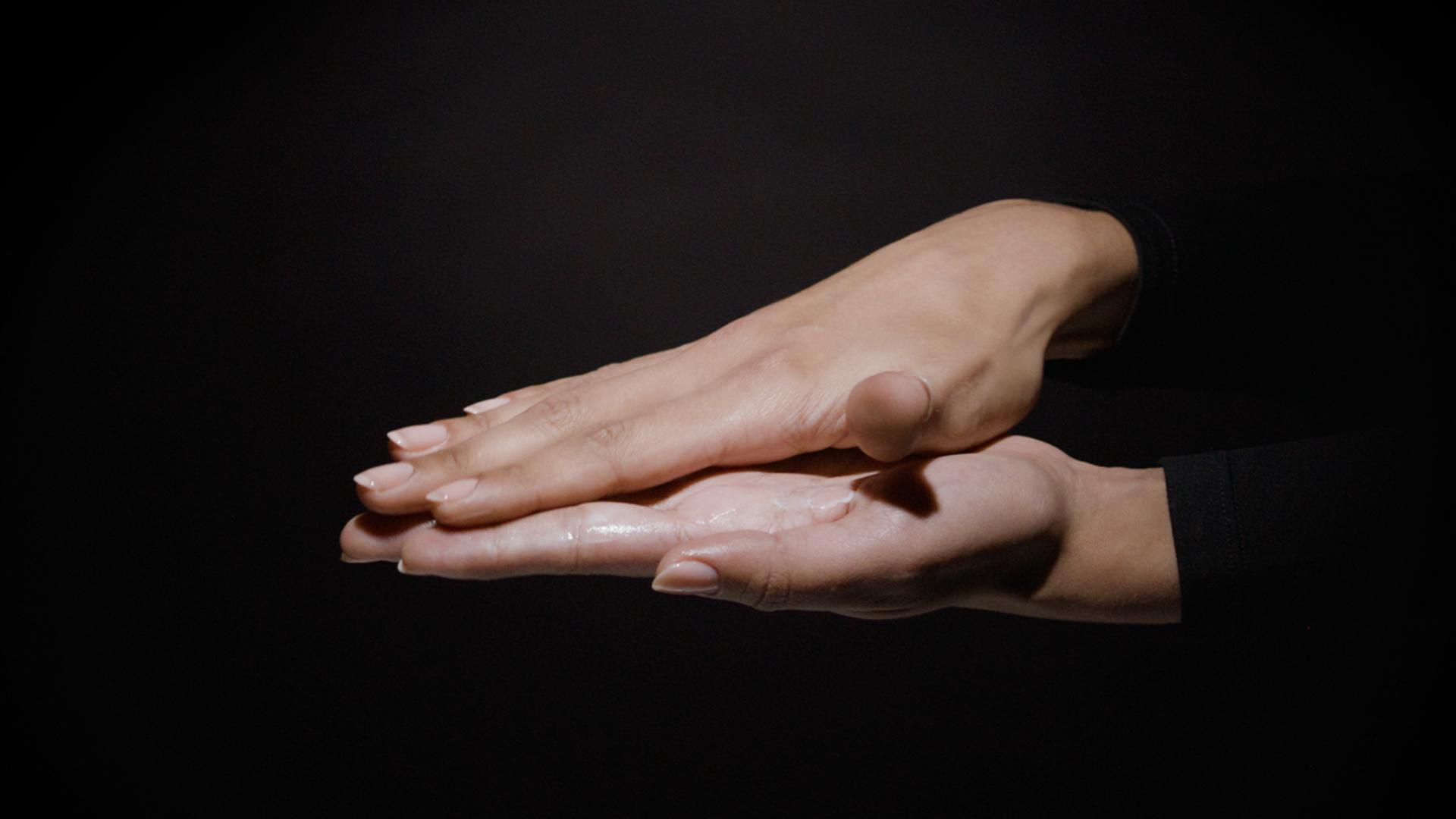 Two hands rub product between the palms.