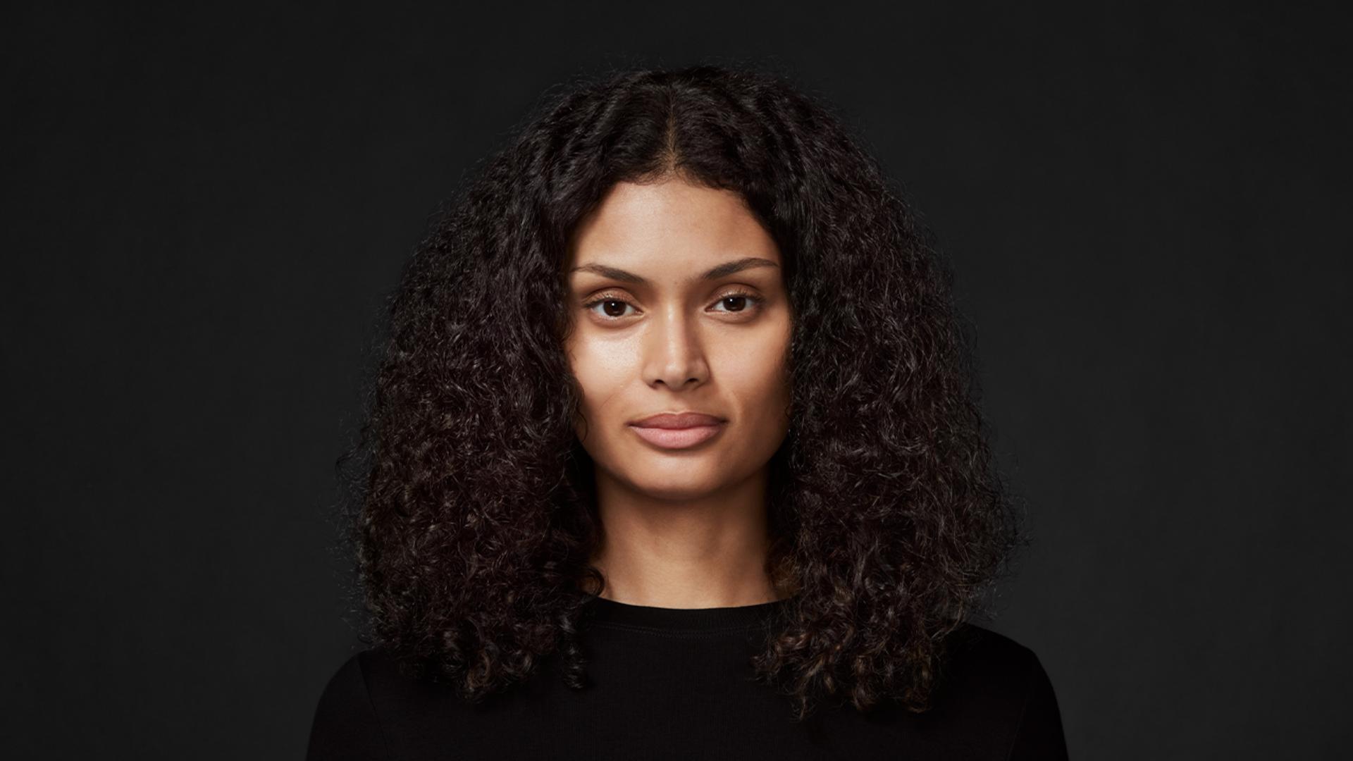 Mode with long, curly, thick hair, against a dark background.