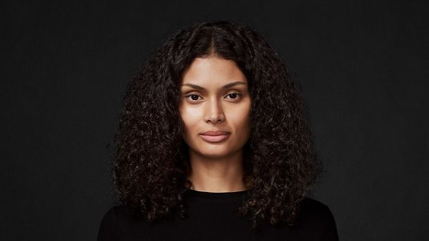 Model with long, curly, thick hair, against a dark background.
