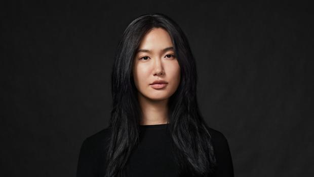 Model with long, straight, thick hair, against a dark background.