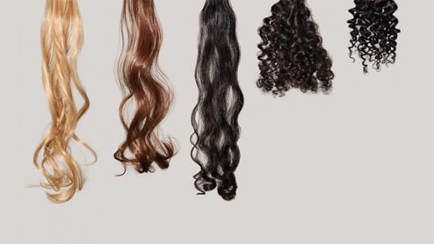 Curly and coily hair tresses clipped to a metal bar, in a lab setting.