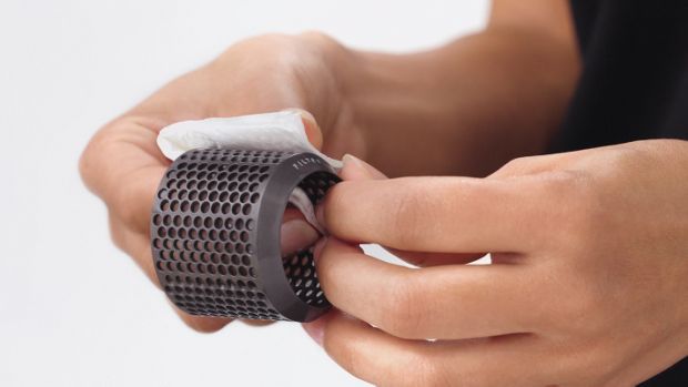 User pinches filter fabric cage dry with paper towel.
