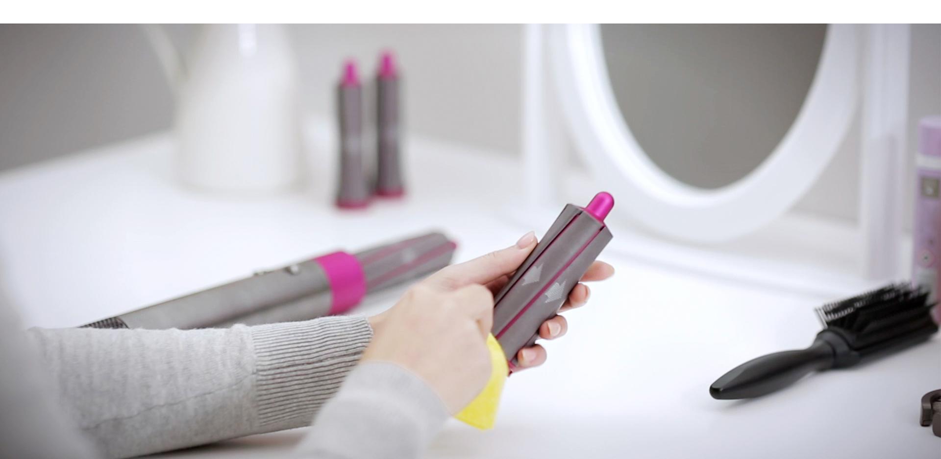 User wipes the styler's barrel with a soft, damp cloth.