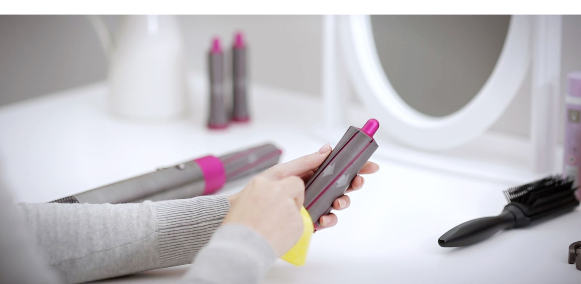 User wipes the styler's barrel with a soft, damp cloth.