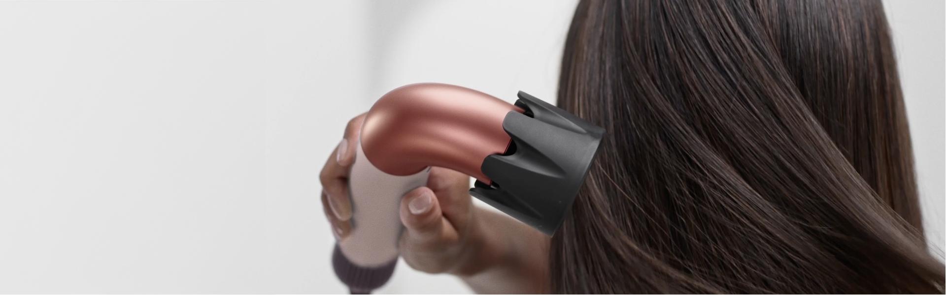 Modelka suszy włosy suszarką do włosów Dyson Supersonic r z końcówką susząca silnym strumieniem.