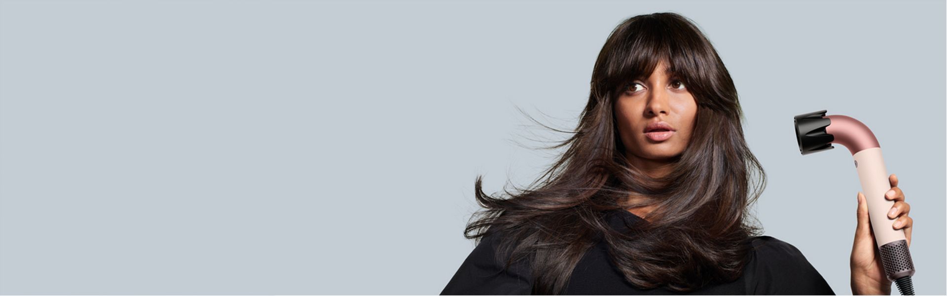 A Dyson Supersonic r hair dryer is used by a model to dry her long brown hair.