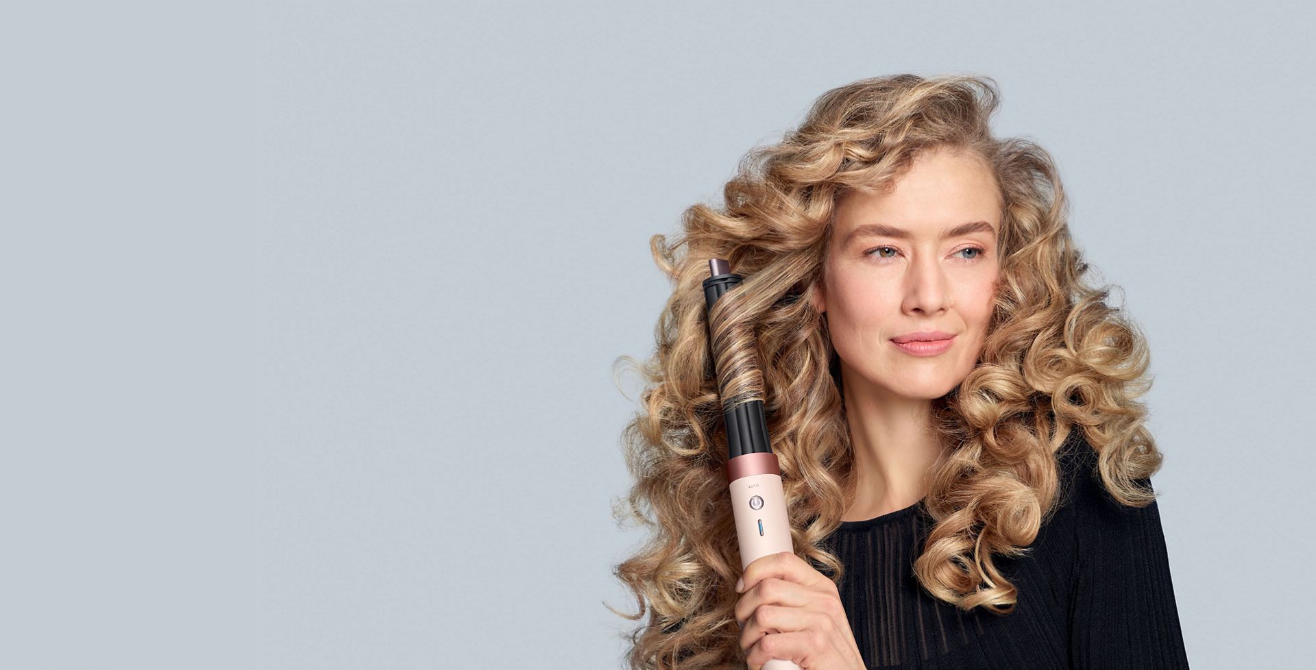 A model diffuses her coily hair using the Dyson Airwrap Co-anda2x multi-styler and dryer.