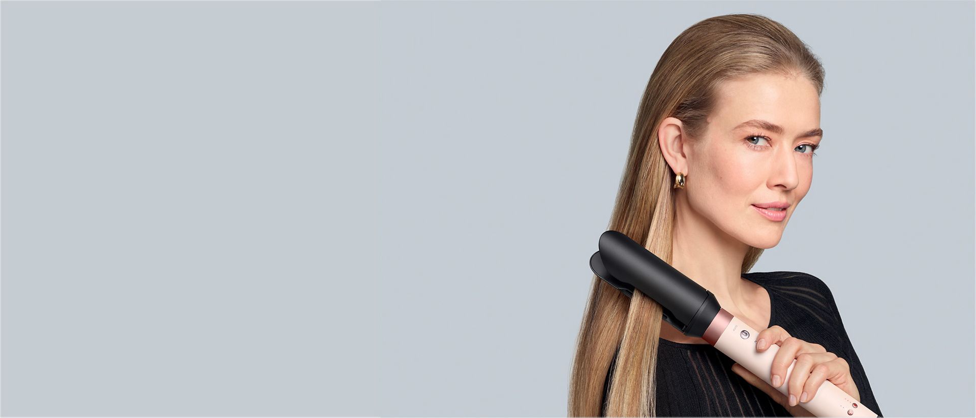 A model with dark hair adds curls using the Dyson Airwrap Co-anda2x multi-styler and dryer.