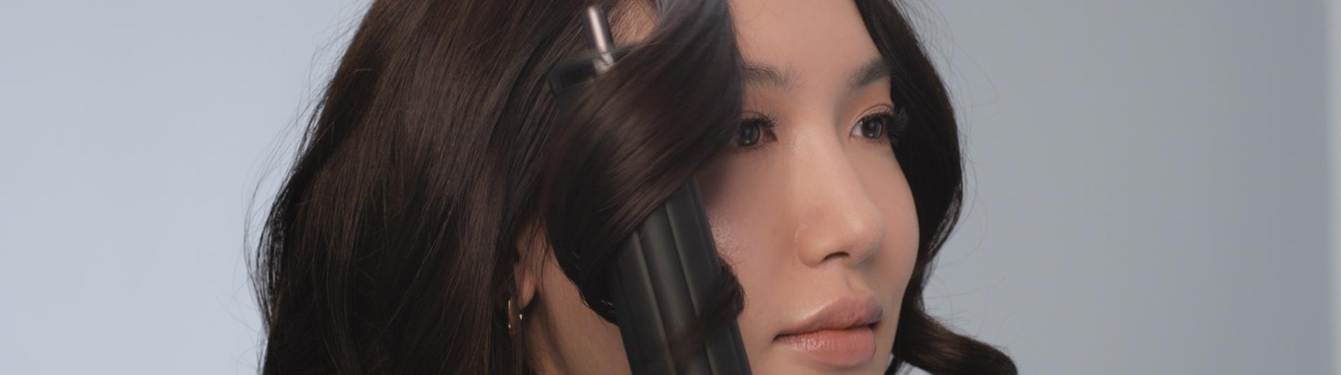 شاشة مقسّمة يظهر فيها مجفف ومصفف Dyson Airwrap Co-anda2x متعدد الوظائف إلى جانب عارِضة شقراء شعرها مُصفَّف باستخدام الجهاز.