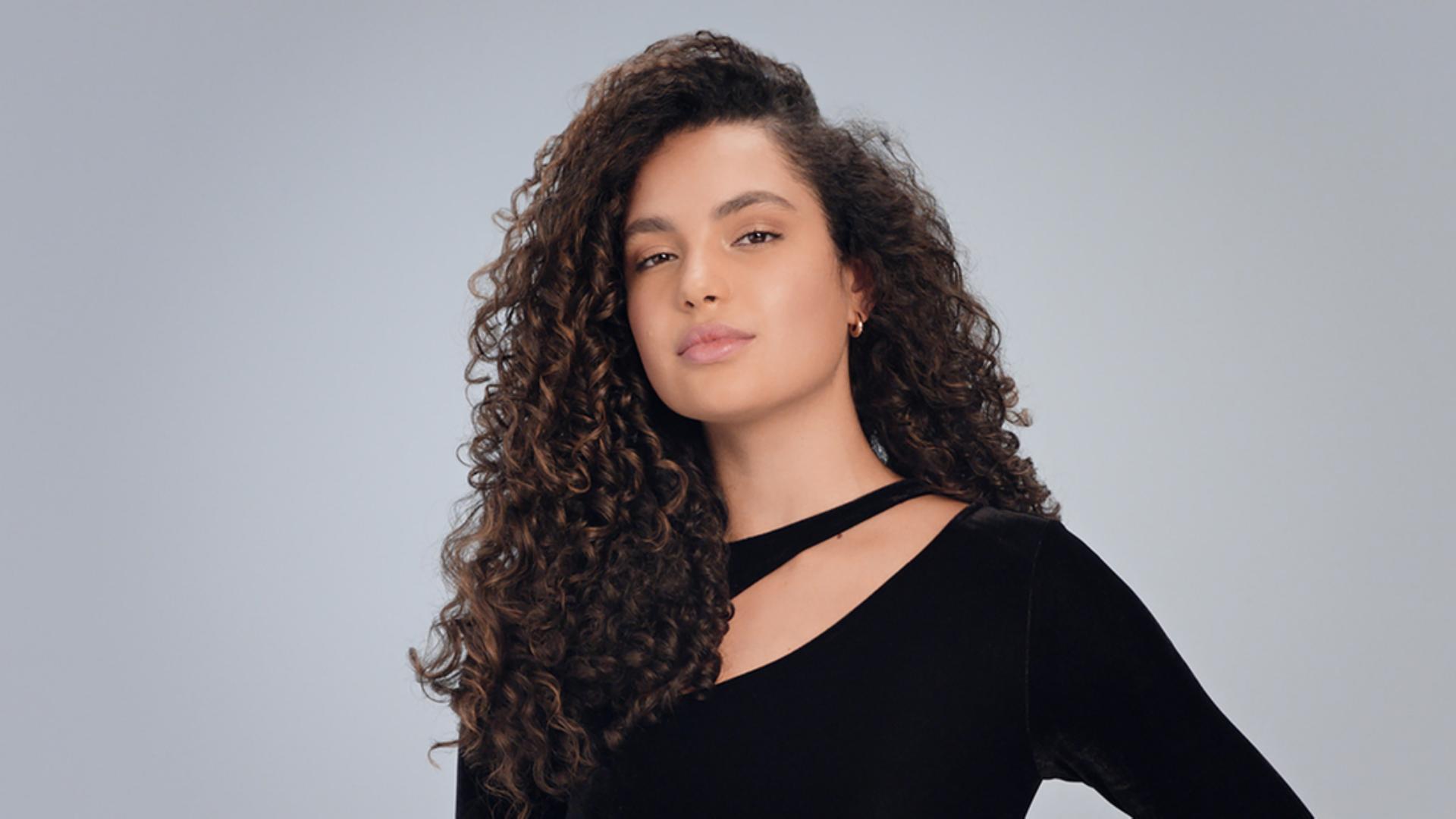 นางแบบผมสีเข้มที่จัดแต่งทรงให้เป็นลอนธรรมชาติสวยเด่นชัด