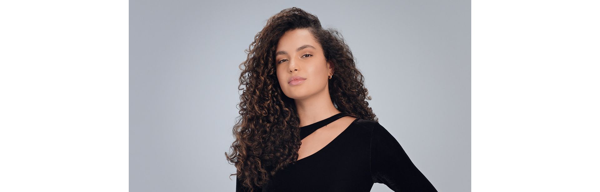 Model with long, curly dark hair styled with the Dyson Airwrap Co-anda2x Wave+Curl diffuser 2x.