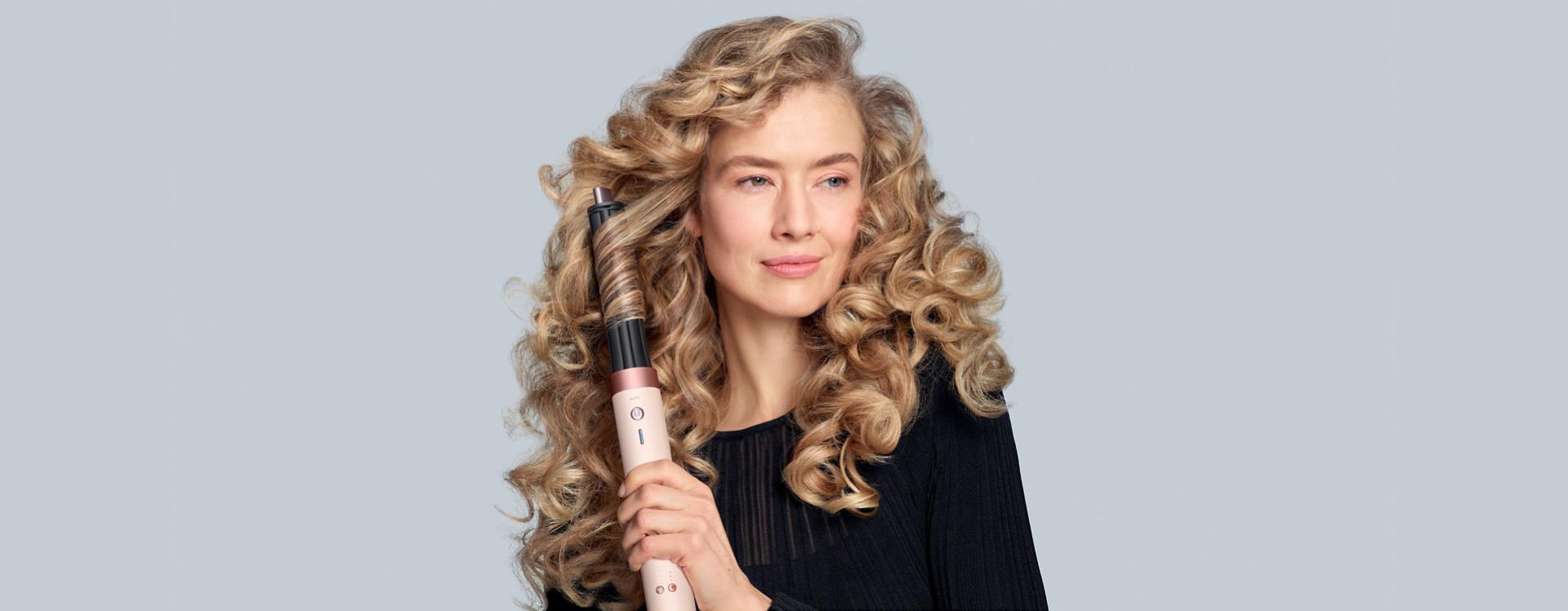 A model diffuses her coily hair using the Dyson Airwrap Co-anda2x multi-styler and dryer and the Wave+Curl diffuser 2x.