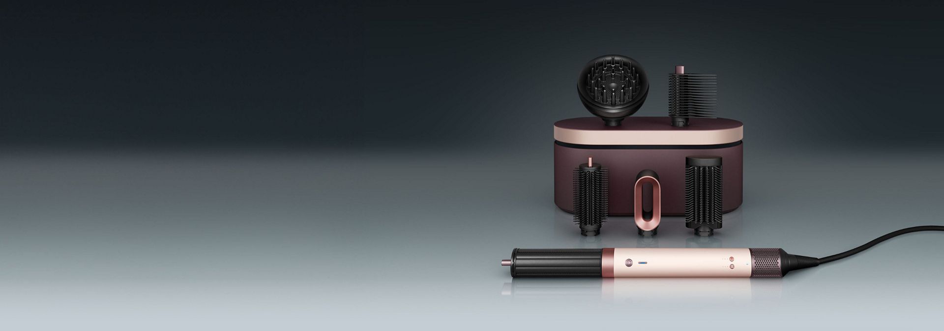 İçinde aksesuarların bulunduğu bir saklama kutusunun önünde duran Dyson Airwrap Co-anda2x saç şekillendirme ve kurutma seti.