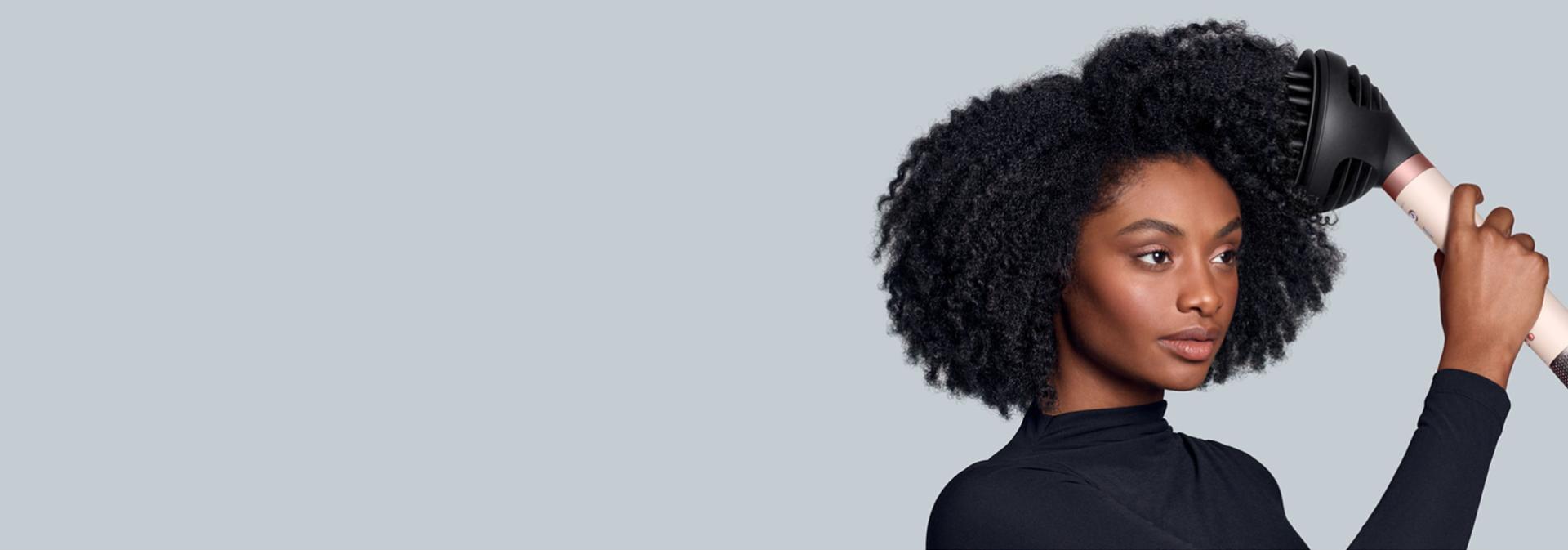 The Dyson Airwrap Co-anda2x multi-styler and dryer with the Wave+Curl Diffuser 2x attachment used by a model.