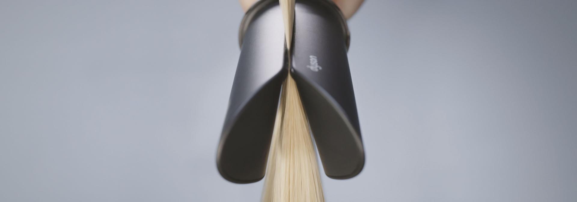 The Dyson AirSmooth2x attachment straightens a tress of blonde hair.