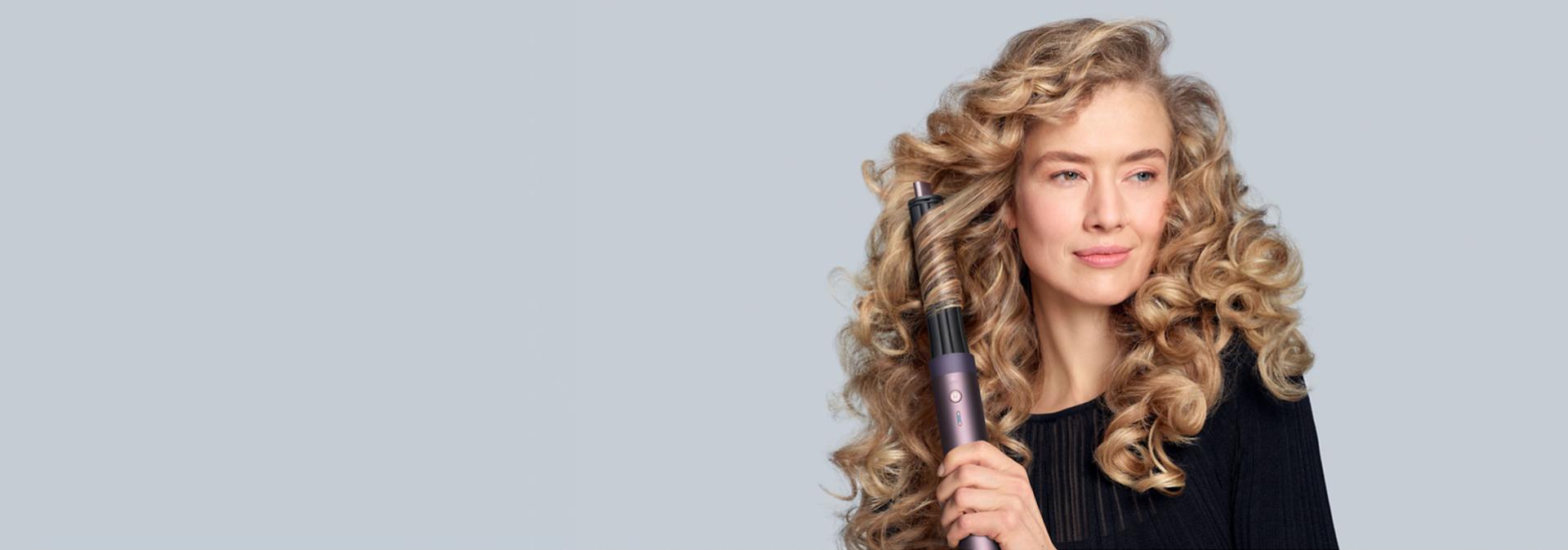 A model with blonde hair adds curls using the Dyson Airwrap Co-anda2x multi-styler and dryer.