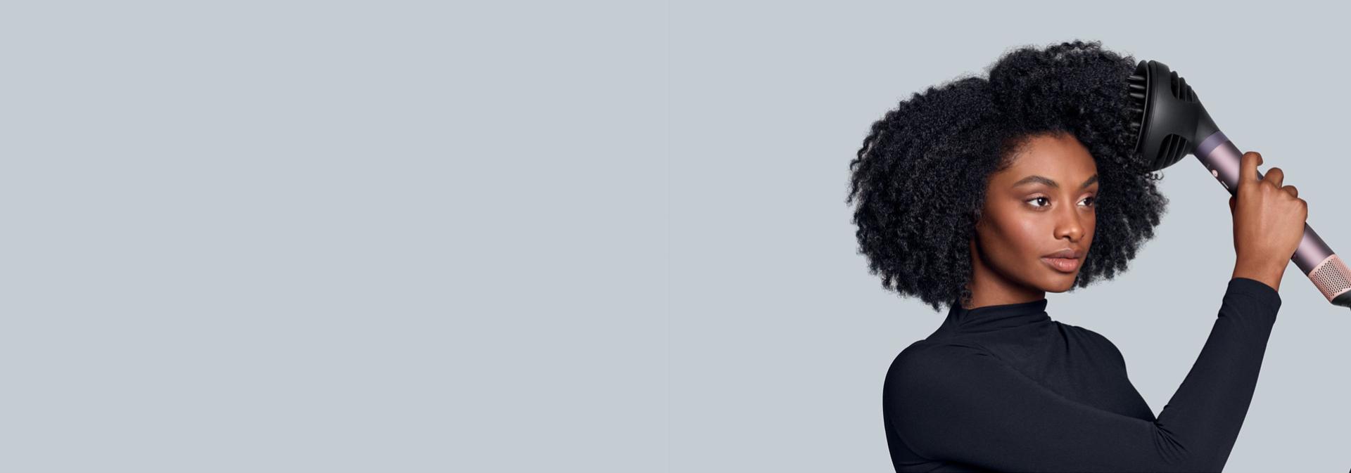 Modelka stylizuje włosy za pomocą multistylera Dyson Airwrap Co-anda2x oraz dyfuzora Wave+Curl 2x.