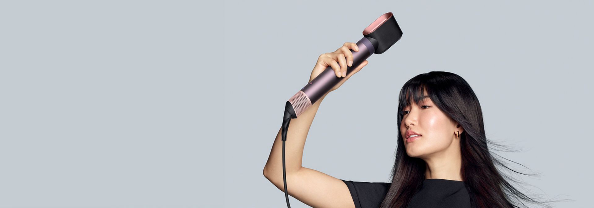 The Dyson Airwrap Co-anda2x multi-styler and dryer with the Fast dryer 2x attachment used by a model.