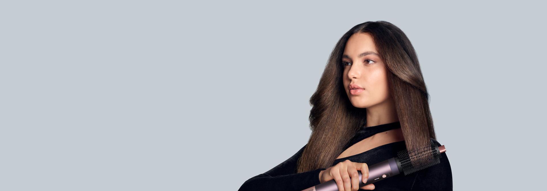 The Dyson Airwrap Co-anda2x multi-styler and dryer with the Round volumising brush 2x attachment used by a model.