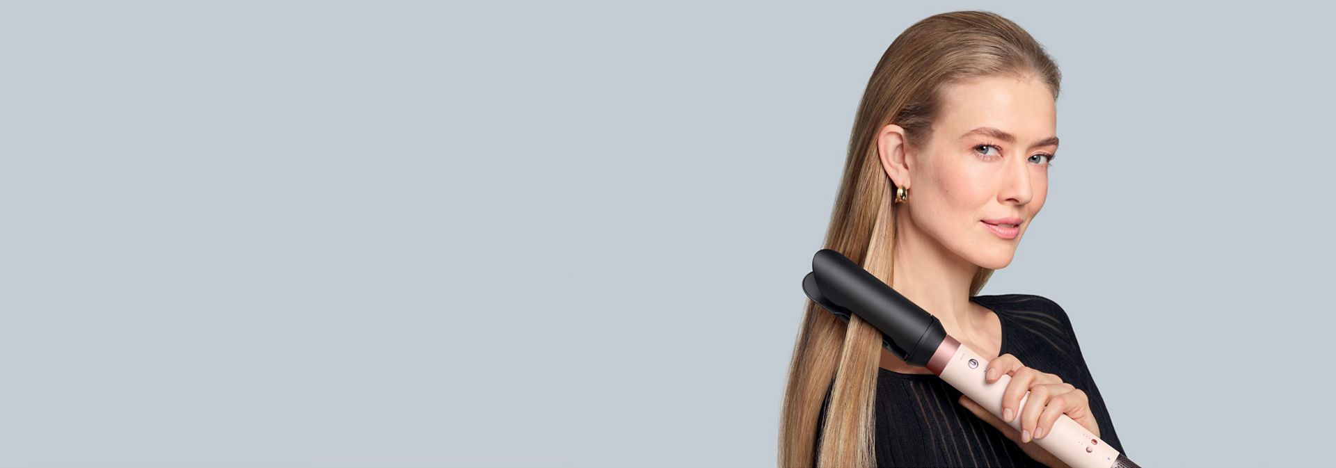 A blonde model straightens her hair using the Dyson Co-anda2x multi-styler and dryer and the AirSmooth2x attachment.