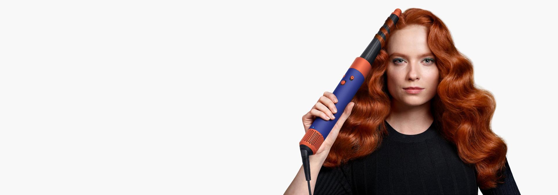 A redhead model curls her hair with the Dyson Airwrap i.d multi-styler and dryer.