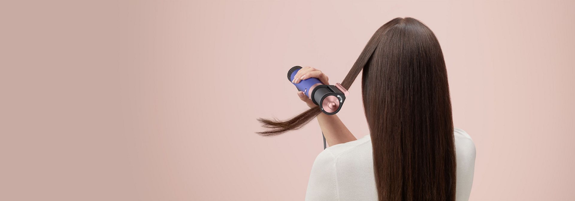 A brunette model smooths flyaways with her Dyson Airwrap Origin multi-styler and dryer.