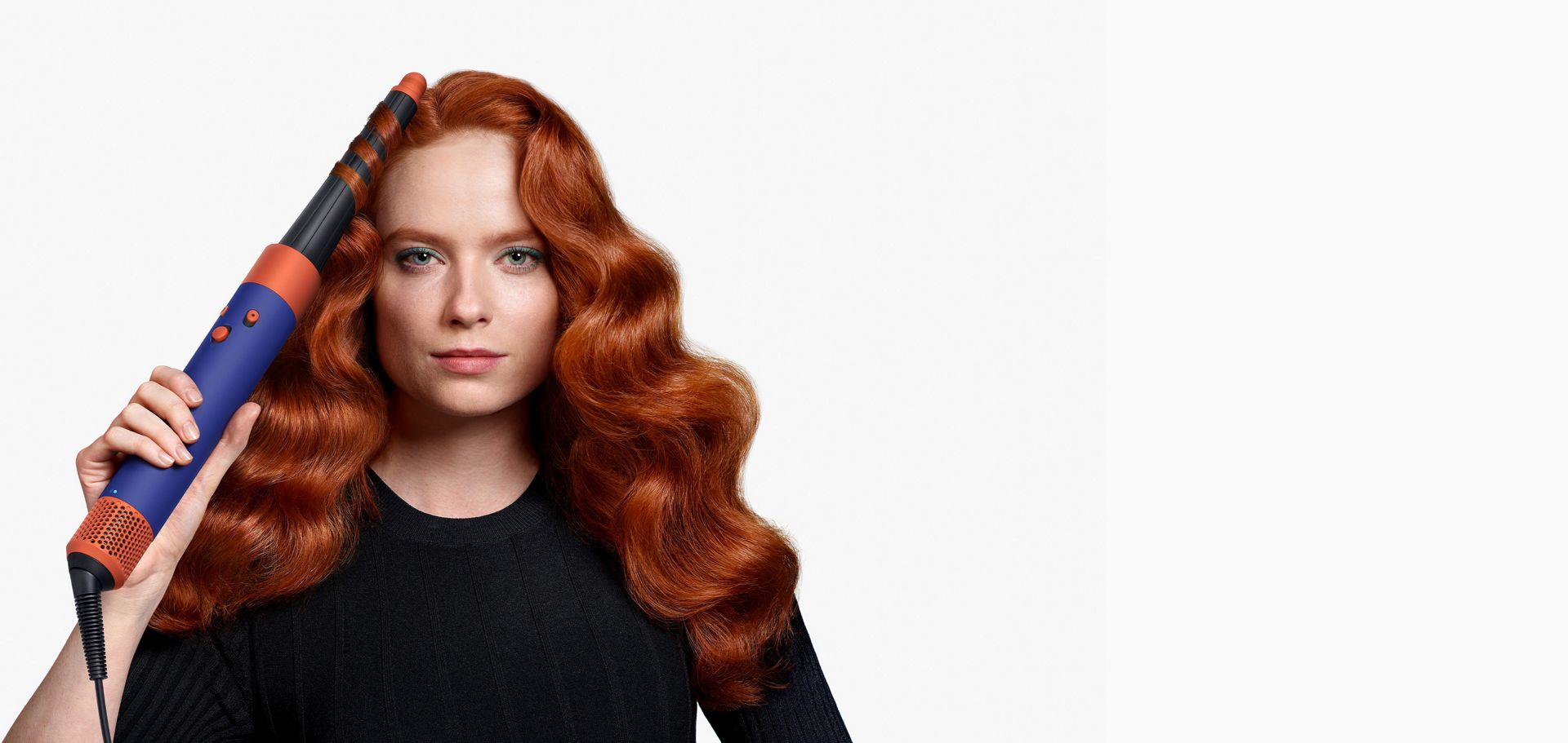 Woman curling hair with a Dyson Airwrap i.d. multi-styler and dryer.