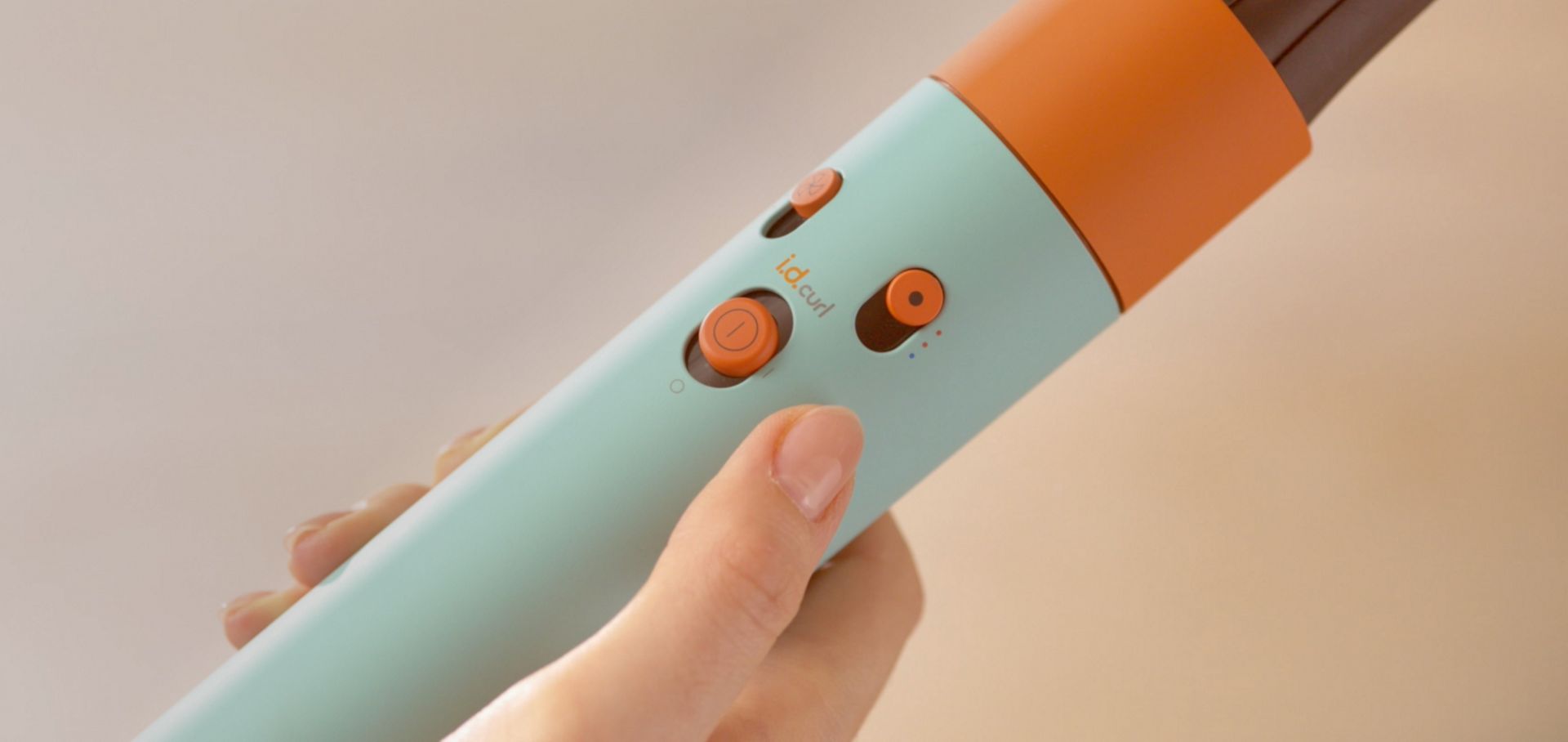 Hand holding the Dyson Airwrap i.d. multi-styler and dryer, with the device's buttons being shown.