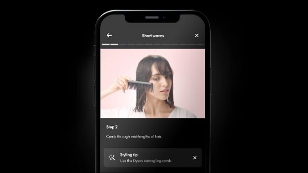 Tālruņa ekrāns, kurā redzamas matu ieveidošanas pamācības lietotnē My Dyson.