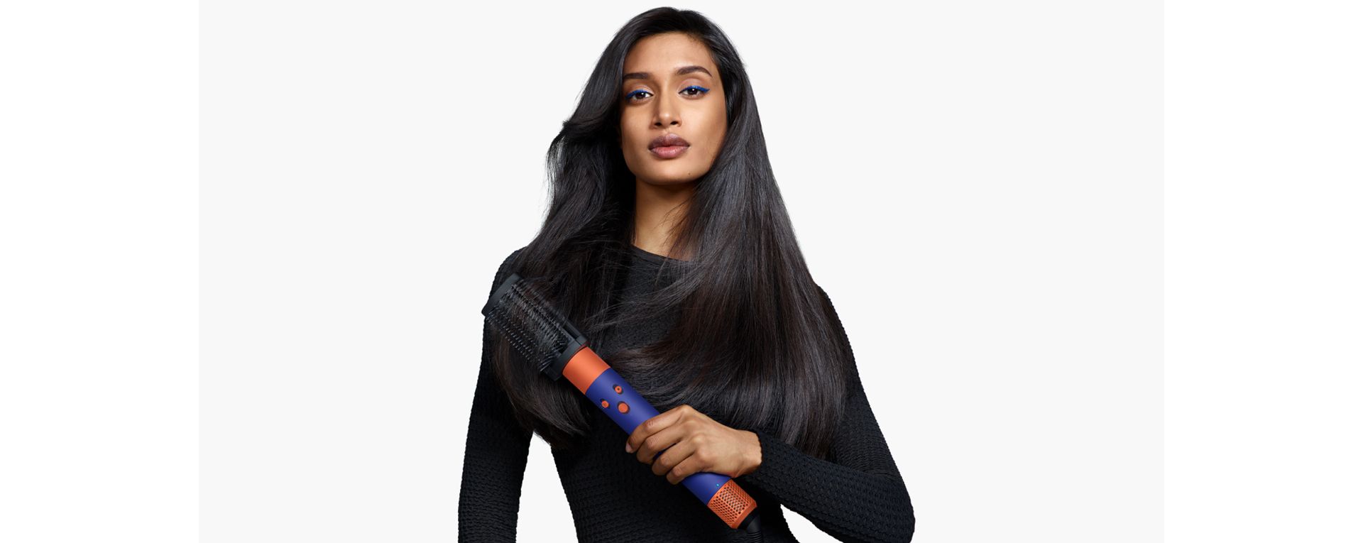 Model holding a Dyson Airwrap i.d. with a 90s blow out style.