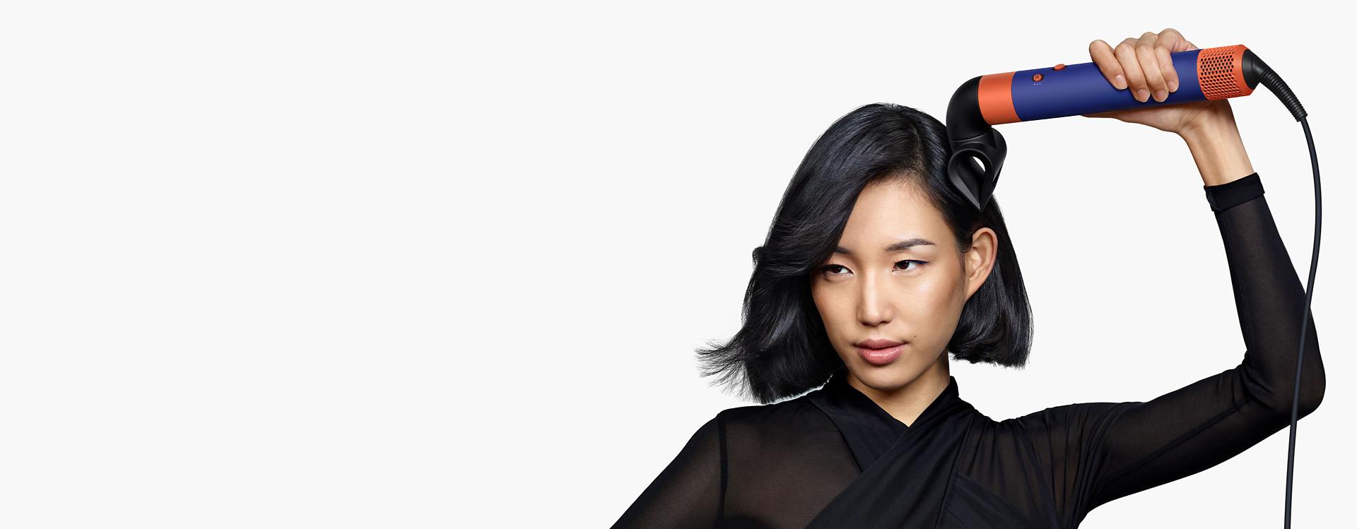 Dyson Airwrap saç şekillendirme ve kurutma seti için odaklı şekillendirme başlığı kullanan bir model.