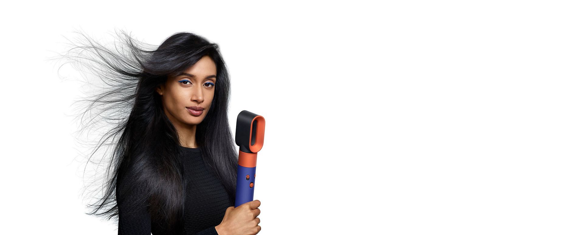 Model holding Dyson Airwrap while the fast dryer blows her hair.