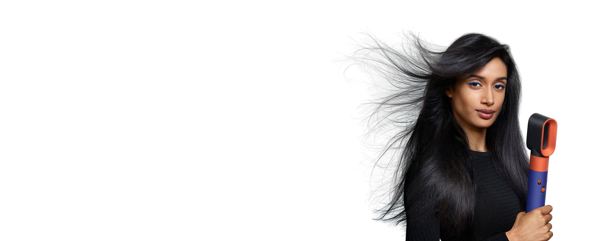 Model holding Dyson Airwrap while the fast dryer blows her hair.