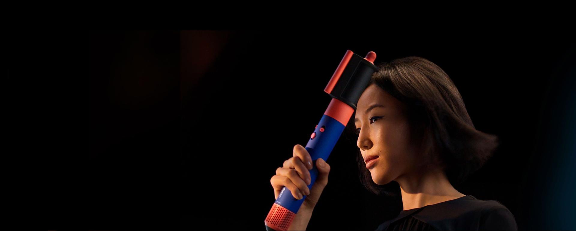 Model with coily hair using the dryer and flyaway smoother.
