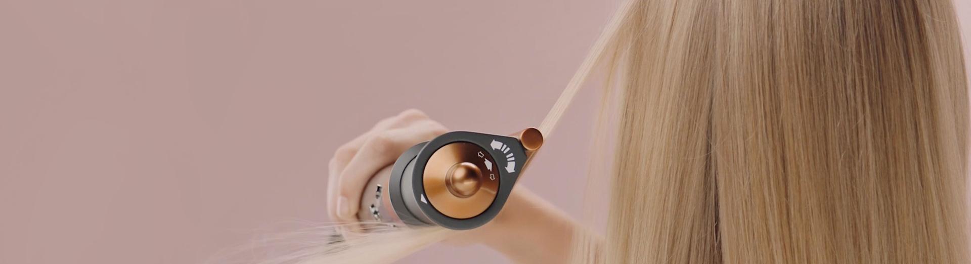 A blonde model uses the Dyson Airwrap multi-styler and dryer with the 2-in-1 Coanda smoothing dryer to style her hair.