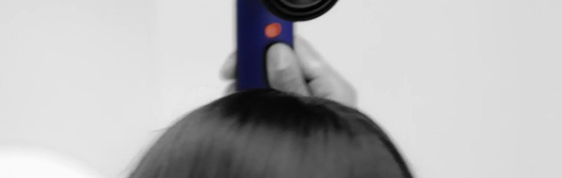 Model dries hair with Dyson Supersonic r Professional hair dryer.