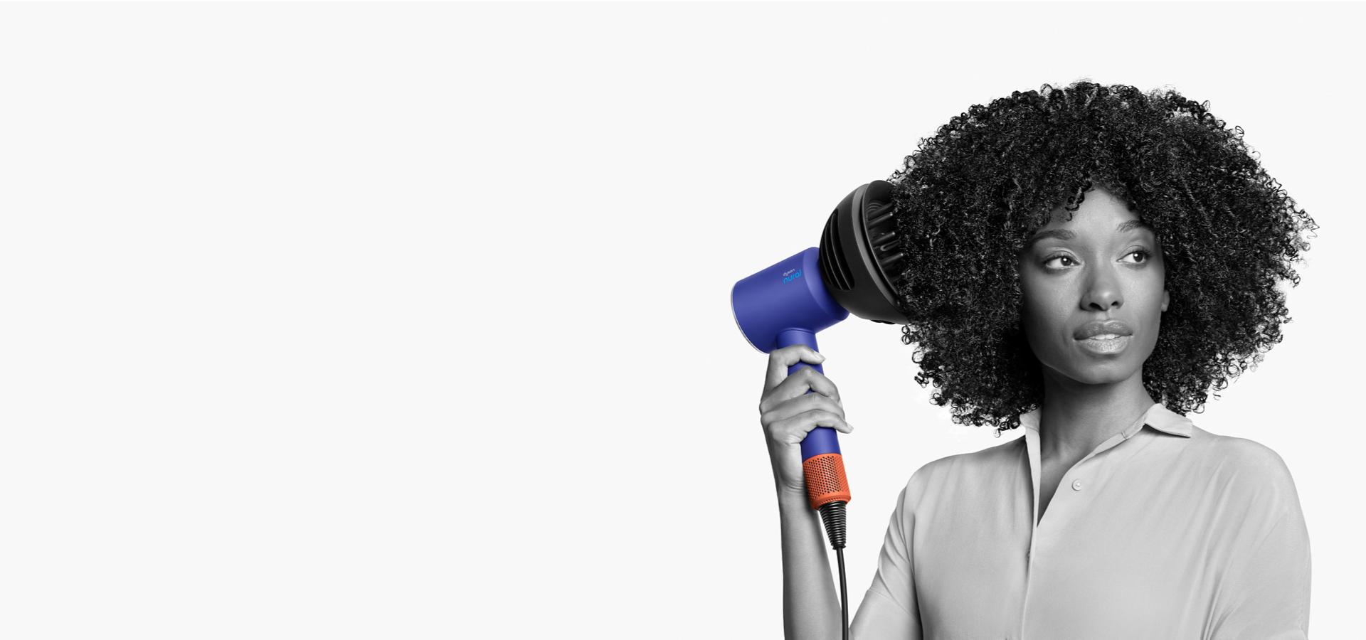 Dyson Supersonic Nural saç kurutma makinesi kullanan bir kadın model.