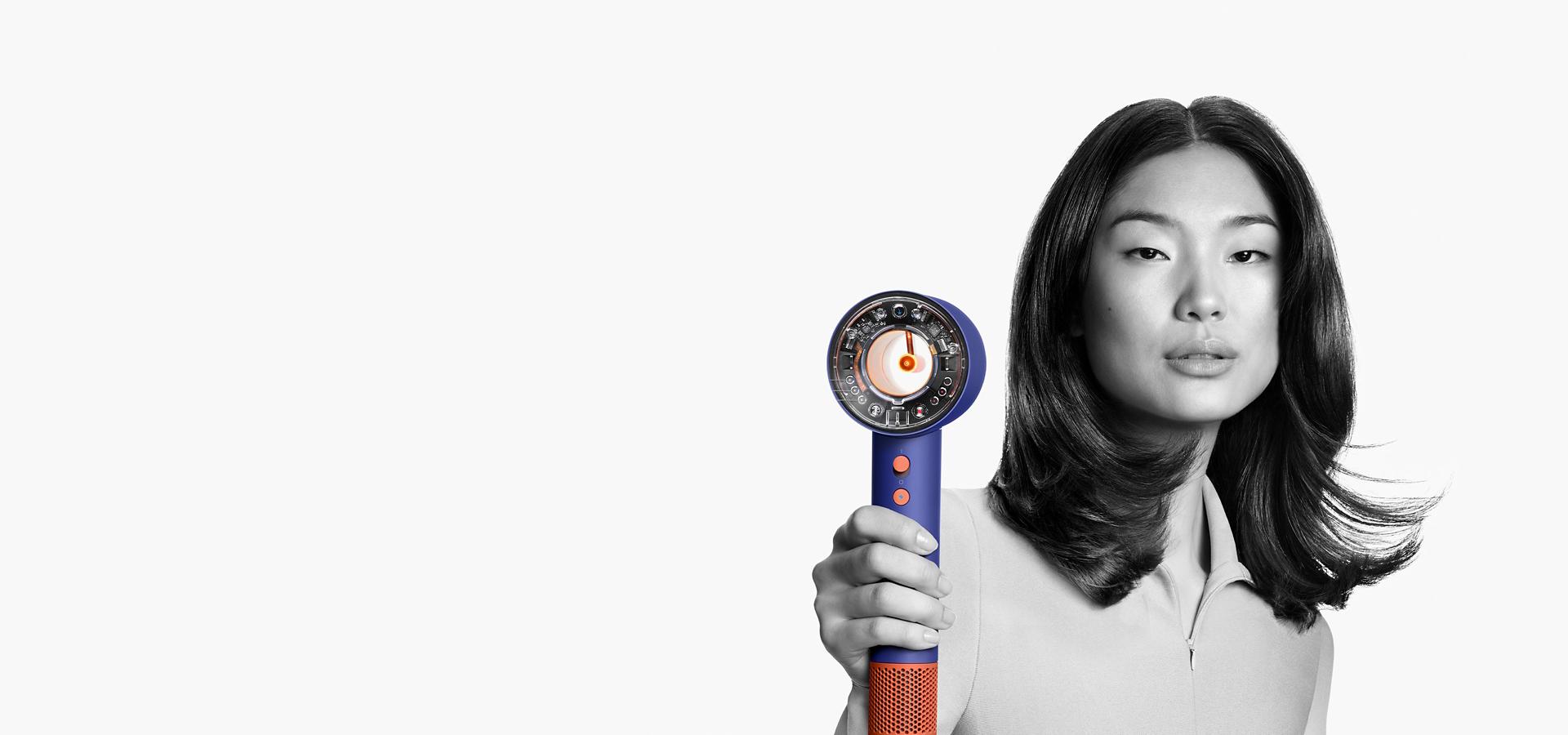A female model using a Dyson Supersonic Nural hair dryer