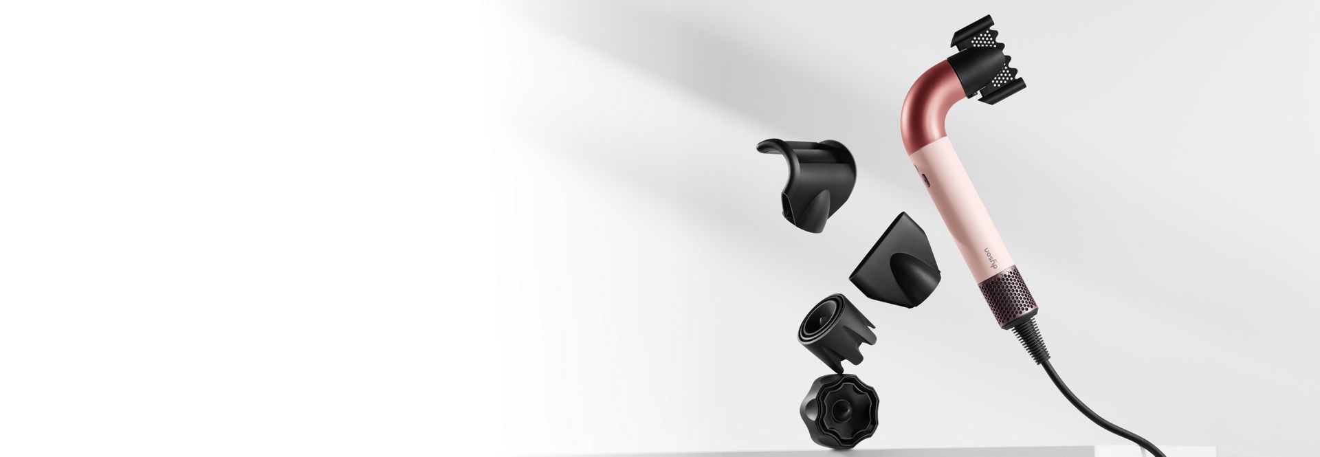 „Dyson Supersonic r“ plaukų džiovintuvas apsuptas įvairių antgalių.