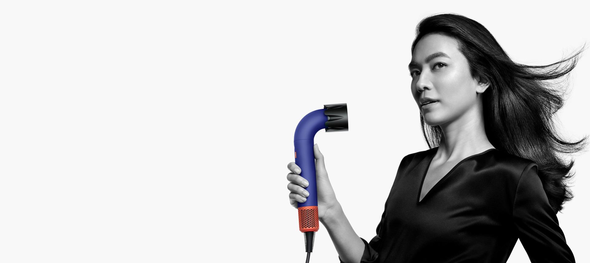 Model using the Dyson Supersonic r to dry her hair with the Powerful air attachment.