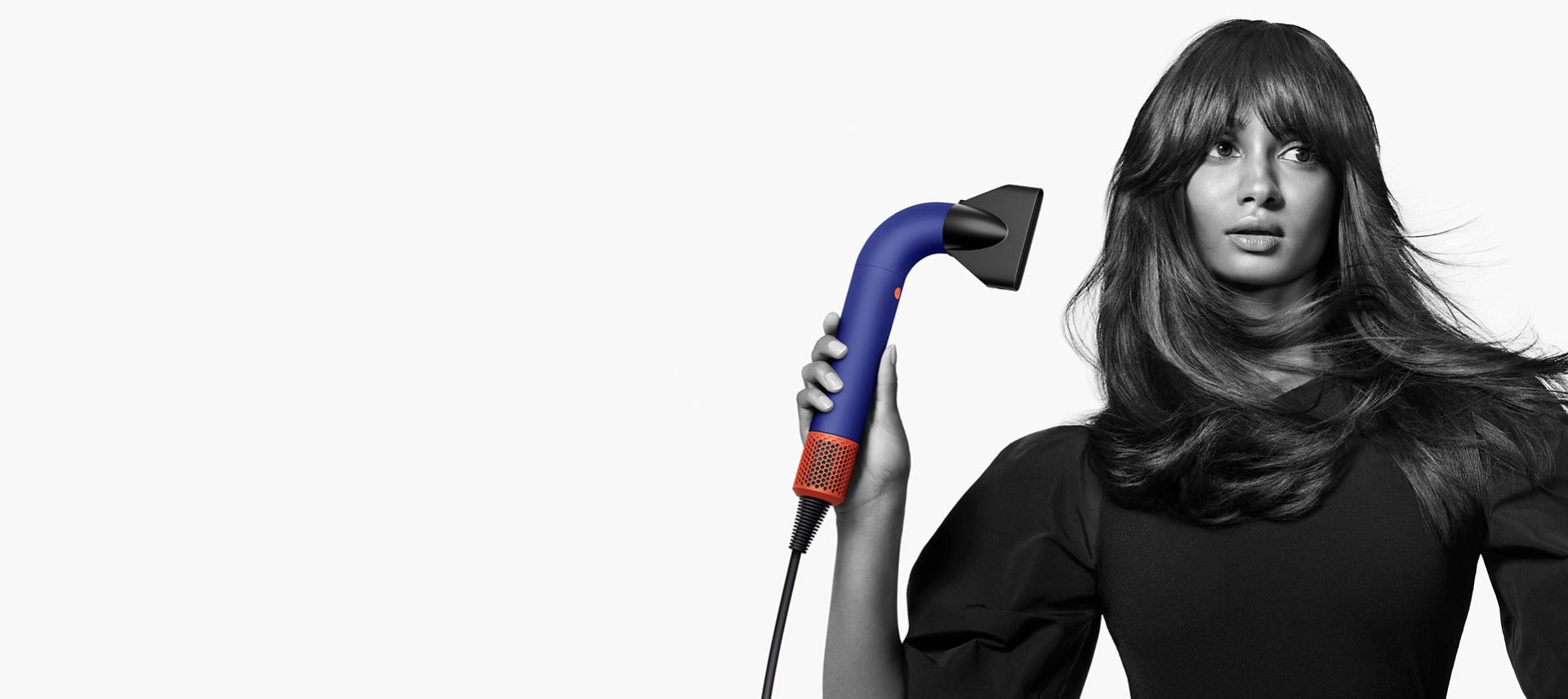Model using the Dyson Supersonic r to dry her hair with the Powerful air attachment.