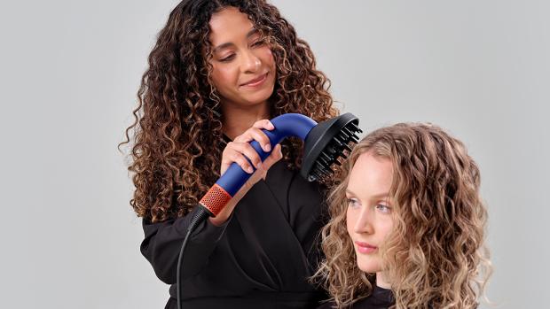 Dyson Supersonic r™ Professional hair dryer being used by a stylist on a woman.