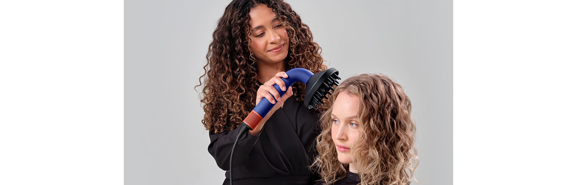 Dyson Supersonic r™ Professional hair dryer being used by a stylist on a woman.
