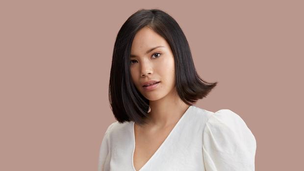 Modelka o brązowych włosach ułożonych we fryzurę pełną blasku przy pomocy suszarki do włosów Dyson Supersonic r.