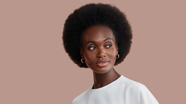 Modelka o brązowych włosach wstylizowanych na afro przy pomocy suszarki do włosów Dyson Supersonic r.