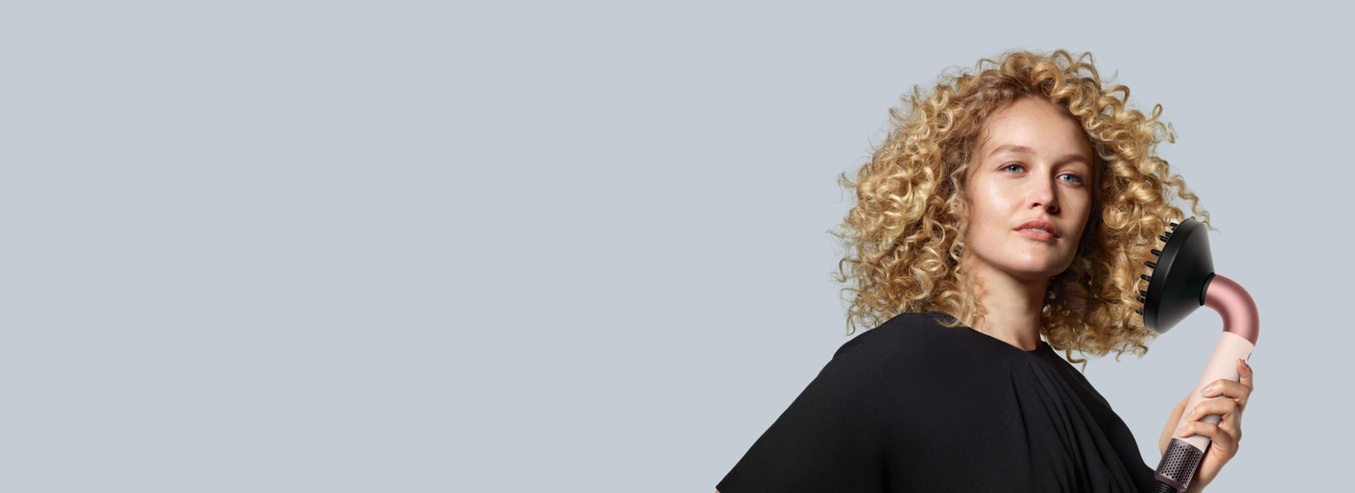 นางแบบผมบลอนด์หยิกถือเครื่องเป่าผม Dyson Supersonic r พร้อมหัวเป่ากระจายลม